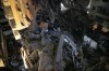 Civilians stand on the wreckage of a destroyed building that was hit by an Israeli airstrike in the southern suburbs of Beirut, Lebanon, Tuesday, July 30, 2024. An Israeli airstrike hit Hezbollah's stronghold south of Beirut Tuesday evening causing damage, a Hezbollah official and the group's TV station said. (AP Photo/Hussein Malla)