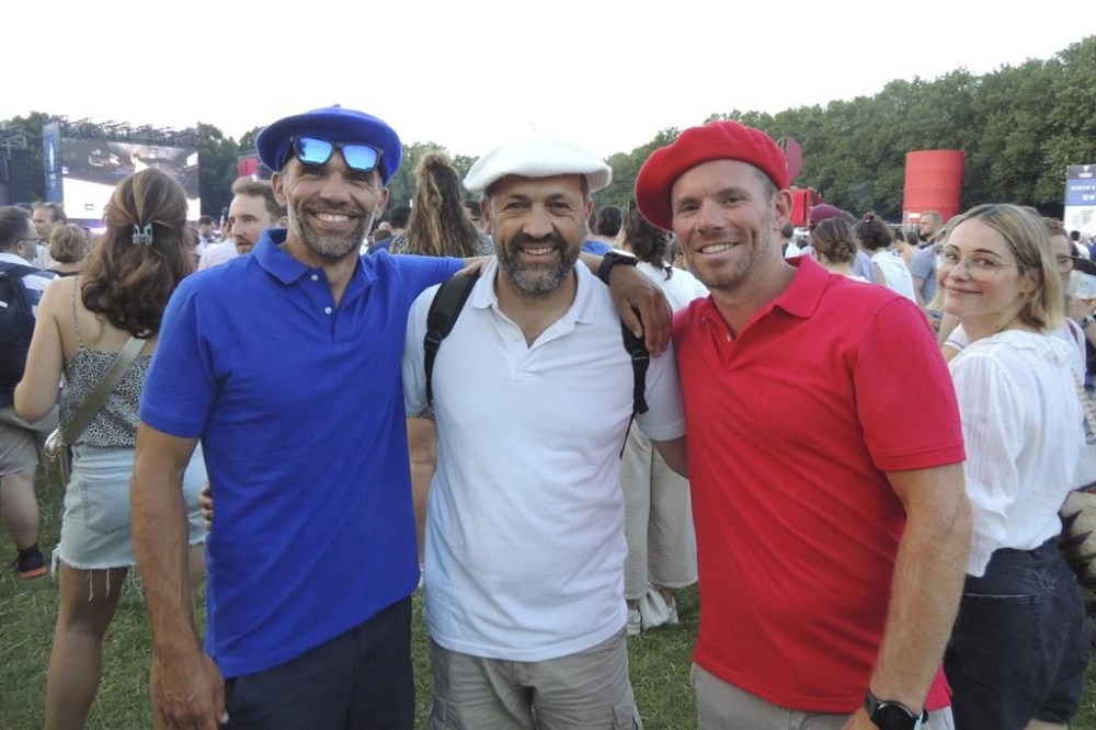 Three fans dressed in the color of the French flag, Martin Puyge, left, André Marais, center, and Philippe Bouju, right, in Club France, an Olympic fan zone, in northern Paris, France, Tuesday, July 30, 2024. (AP Photo/Tom Nouvian)