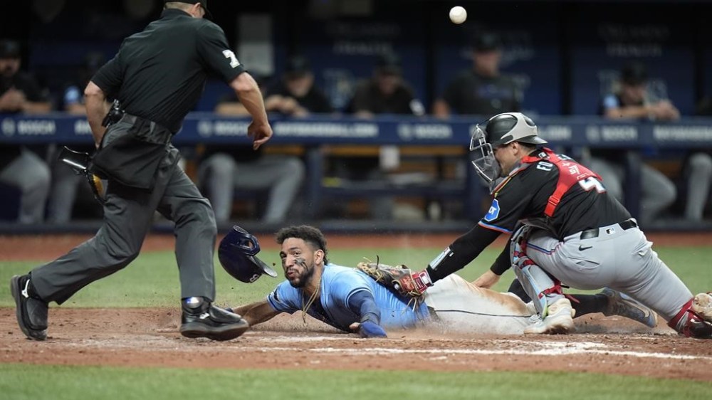 Tampa Bay Rays' Jose Caballero, center, steals home plate as the ball skips away from Miami Marlins catcher Nick Fortes, right, during the seventh inning of a baseball game Tuesday, July 30, 2024, in St. Petersburg, Fla. Making the call is home plate umpire Tripp Gibson. (AP Photo/Christopher O'Meara)