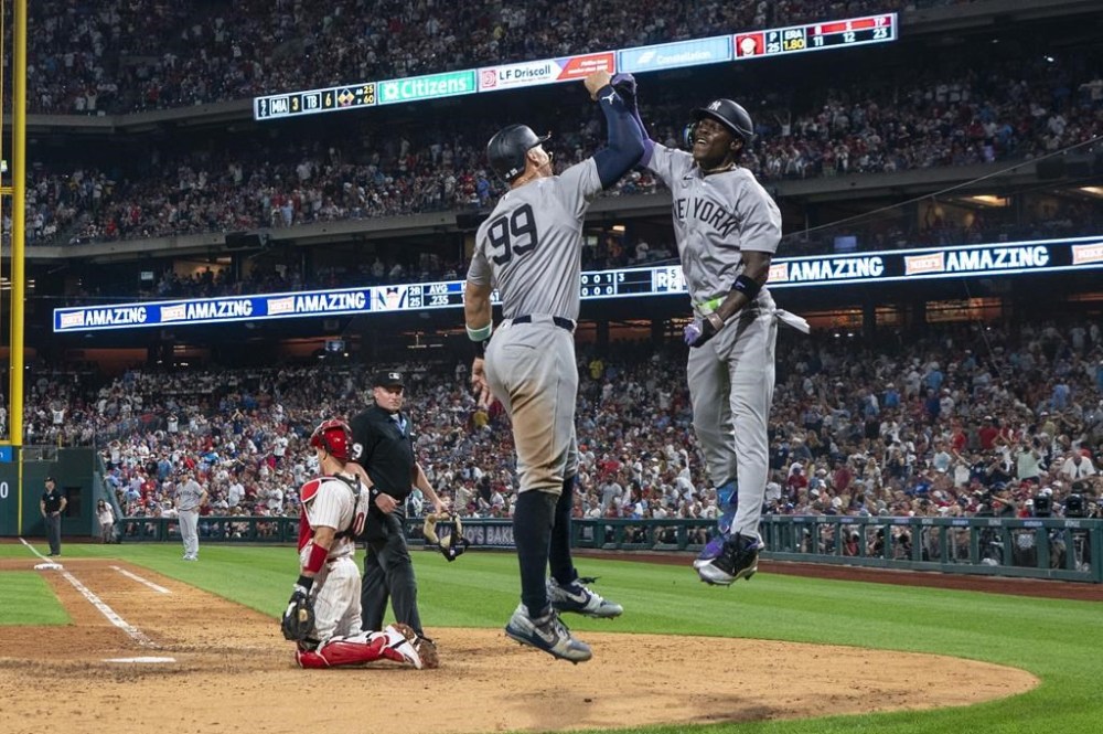 New York Yankees' Jazz Chisholm Jr., right, celebrates his three-run home run with Aaron Judge, center, as Philadelphia Phillies catcher J.T. Realmuto, left, looks on during the seventh inning of a baseball game, Tuesday, July 30, 2024, in Philadelphia. (AP Photo/Chris Szagola)