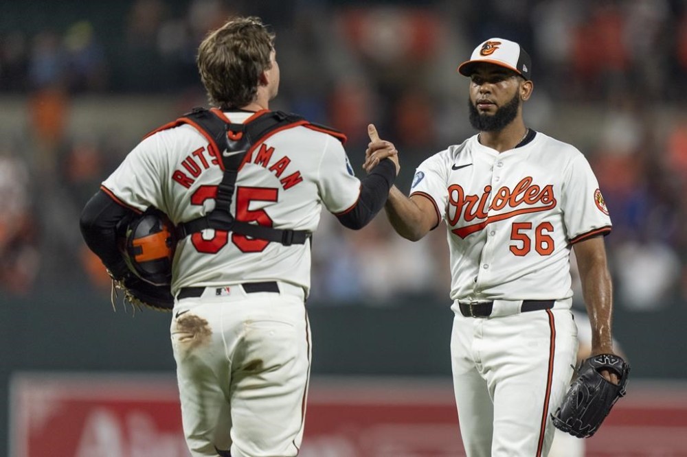 Baltimore Orioles catcher Adley Rutschman (35) and relief pitcher Seranthony Dominguez (56) celebrate their team's win over the Toronto Blue Jays after a baseball game, Tuesday, July 30, 2024, in Baltimore. (AP Photo/Stephanie Scarbrough)