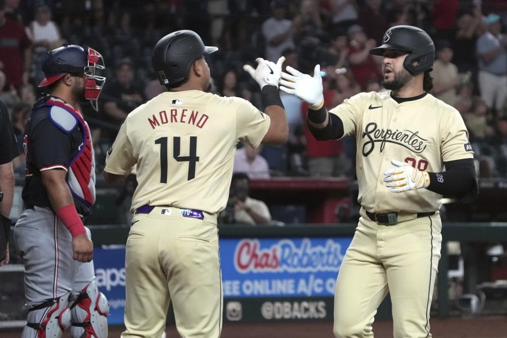 Arizona Diamondbacks' Eugenio Suárez celebrates with Gabriel Moreno (14) after hitting a two-run home run against the Washington Nationals in the first inning during a baseball game, Tuesday, July 30, 2024, in Phoenix. (AP Photo/Rick Scuteri)