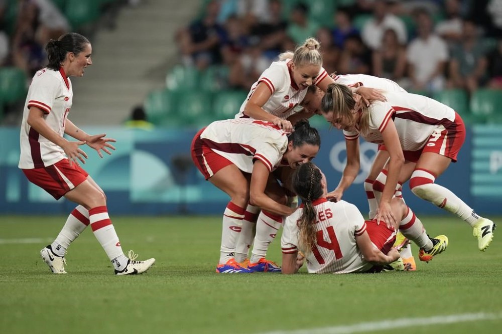 Canada's players celebrate after Vanessa Gilles, bottom centre, scored her side's second goal during the women's Group A soccer match between Canada and France at Geoffroy-Guichard stadium during the 2024 Summer Olympics, Sunday, July 28, 2024, in Saint-Etienne, France. THE CANADIAN PRESS/AP/Silvia Izquierdo