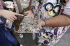Vivianne Robinson lets a passer by choose one of the pins Robinson collected from USA Olympics 1984, during 2024 Summer Olympics, in Paris, France, Tuesday, July 30, 2024. The Olympics superfan has attended seven Games over the span of 40 years. (AP Photo/Lujain Jo)