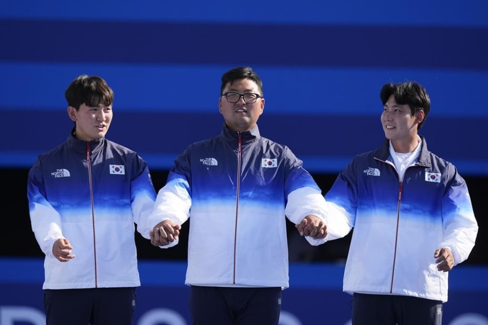 Gold medal winners, South Korea's Je Deok Kim, left, Woojin Kim, center, Wooseok Lee, right, celebrate during the men's team medal ceremony at the 2024 Summer Olympics, Monday, July 29, 2024, in Paris, France. (AP Photo/Rebecca Blackwell)