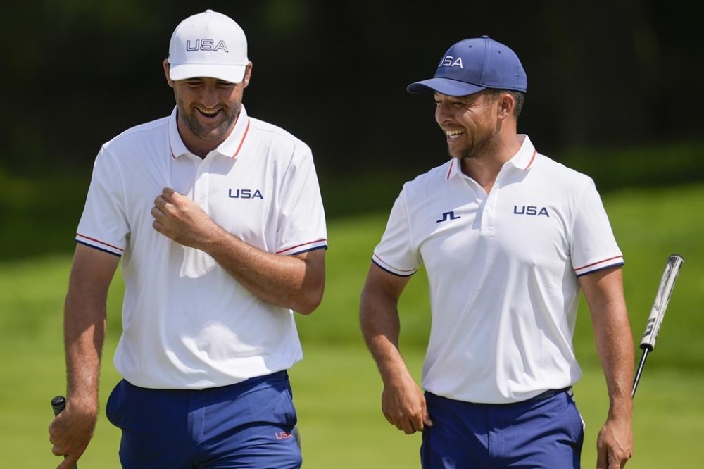 Scottie Scheffler, left, and Xander Schauffele, both of the United States, laugh on the 13th green during a practice round for the men's golf event at the 2024 Summer Olympics, Wednesday, July 31, 2024, at Le Golf National in Saint-Quentin-en-Yvelines, France. (AP Photo/George Walker IV)