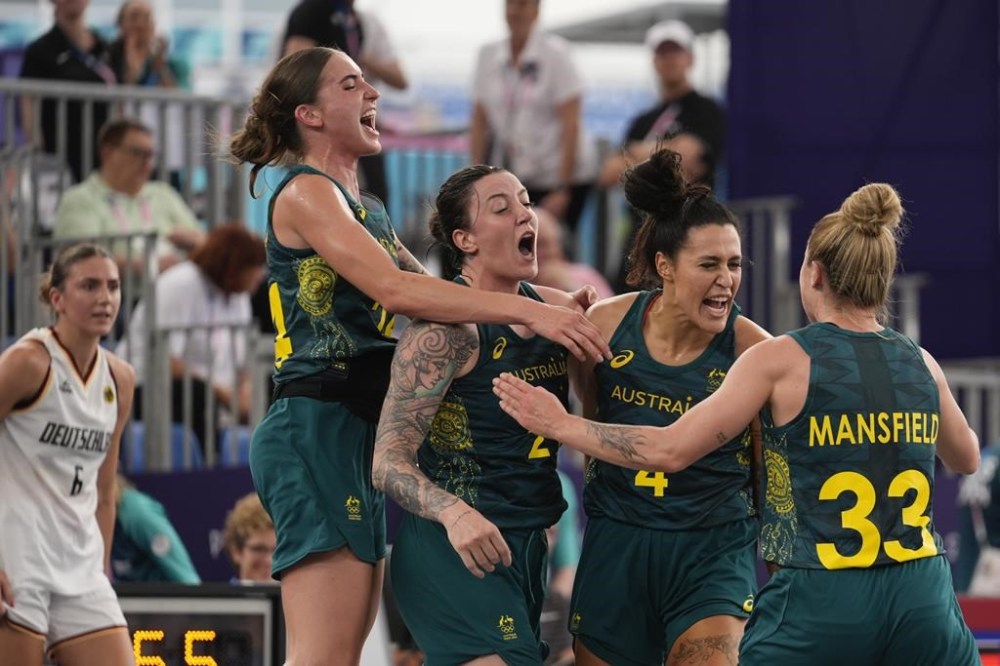 Australia's, from left, Anneli Maley, Marena Whittle, Alex Wilson and Lauren Mansfield celebrate their victory as Germany's Marie Reichert looks on, in the women's 3x3 basketball pool round match between Germany and Australia at the 2024 Summer Olympics, Wednesday, July 31, 2024, in Paris, France. (AP Photo/Rebecca Blackwell)