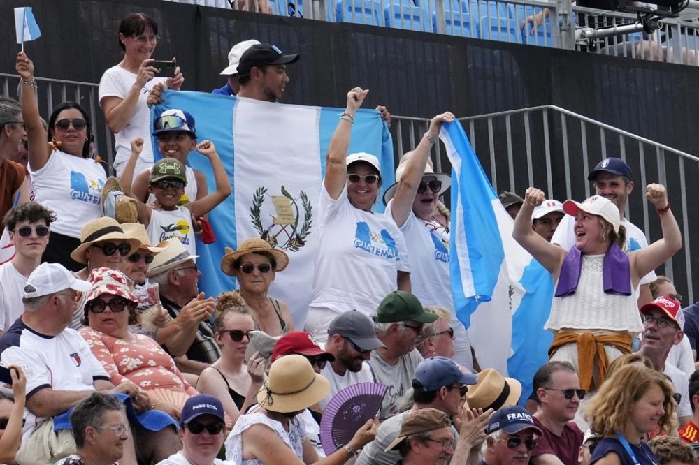 Guatemala's fans cheer for Adriana Oliva Ruano at the Trap women's final at the 2024 Summer Olympics, Wednesday, July 31, 2024, in Chateauroux, France. Guatemala's Adriana Oliva Ruano won the gold medal in the event. (AP Photo/Manish Swarup)