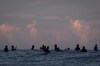 Surfers talk in the lineup before the start of the third round of surfing competition at the 2024 Summer Olympics, Monday, July 29, 2024, in Teahupo'o, Tahiti. (AP Photo/Gregory Bull)