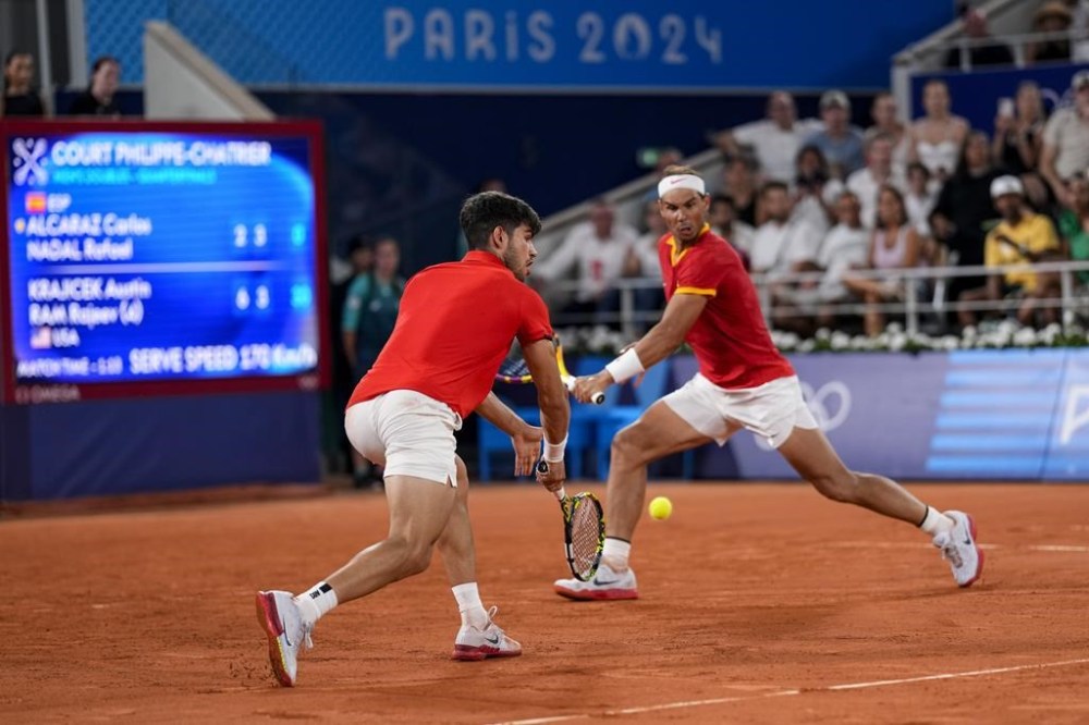 Rafael Nadal, left, and Carlos Alcaraz of Spain return the ball against Austin Krajicek and Rajeev Ram of the USA during the men's doubles quarterfinal tennis competition at the Roland Garros stadium, at the 2024 Summer Olympics, Wednesday, July 31, 2024, in Paris, France. (AP Photo/Manu Fernandez)