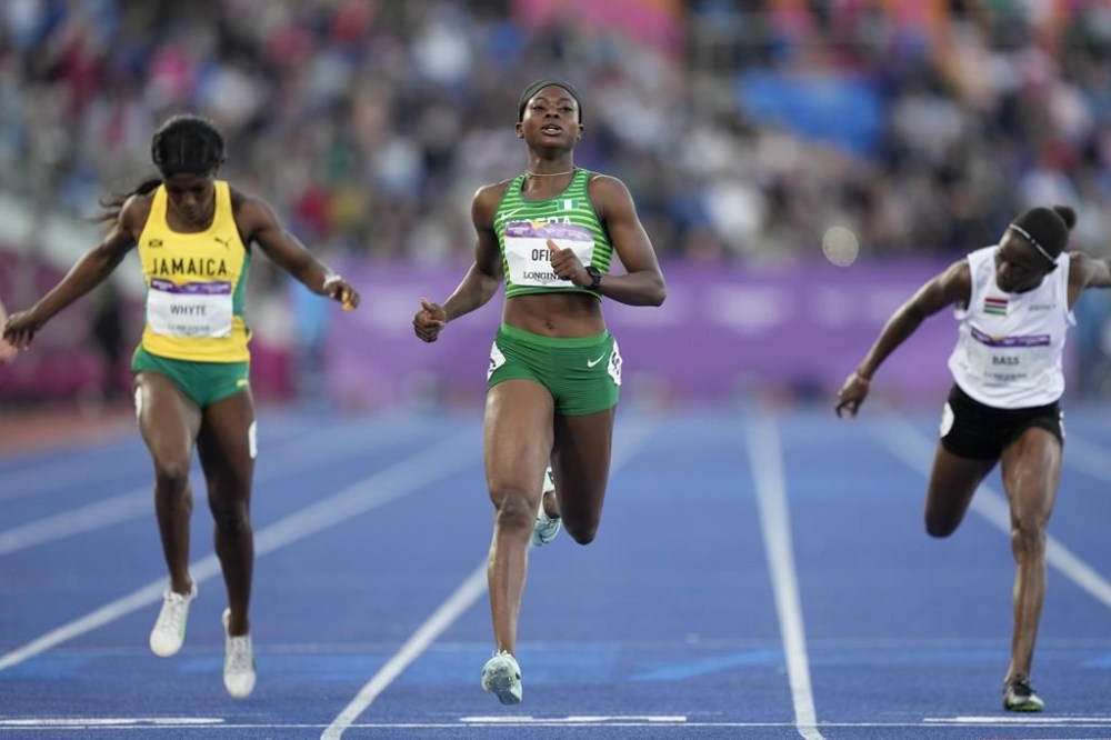 FILE - Favour Ofili of Nigeria, centre crosses the finish line ahed of Natalliah Whyte of Jamaica, left, and Gina Bass of The Gambia, right, in a Women's 200 meters semifinal during the athletics competition in the Alexander Stadium at the Commonwealth Games in Birmingham, England, Friday, Aug. 5, 2022. Nigeria's national champion in the women's 100-meter sprint won't run the race at the Olympics because she says her country's track federation didn't enter her into the field in time. (AP Photo/Manish Swarup, File)