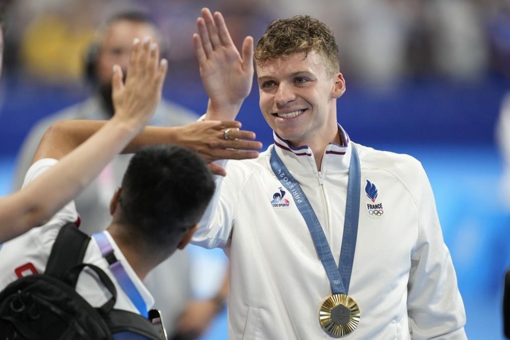 Gold medallist Leon Marchand, of France, greets fans after the men's 200-meter breaststroke final at the 2024 Summer Olympics, Wednesday, July 31, 2024, in Nanterre, France. (AP Photo/Ashley Landis)