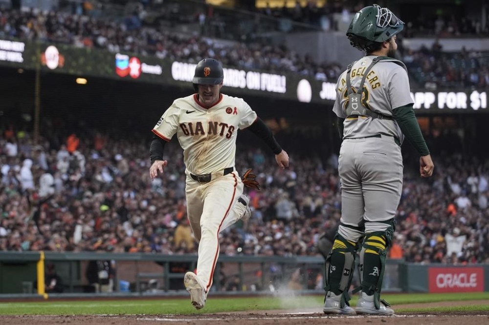 San Francisco Giants' Mike Yastrzemski, left, scores next to Oakland Athletics catcher Shea Langeliers on Brett Wisely's sacrifice fly during the fifth inning of a baseball game Wednesday, July 31, 2024, in San Francisco. (AP Photo/Godofredo A. Vásquez)