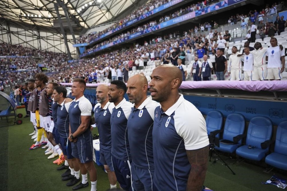 France's head coach Thierry Henry, right, sings the national anthem before the start of the men's Group A soccer match between New Zealand and France, at the Velodrome stadium, during the 2024 Summer Olympics, Tuesday, July 30, 2024, in Marseille, France. (AP Photo/Daniel Cole)