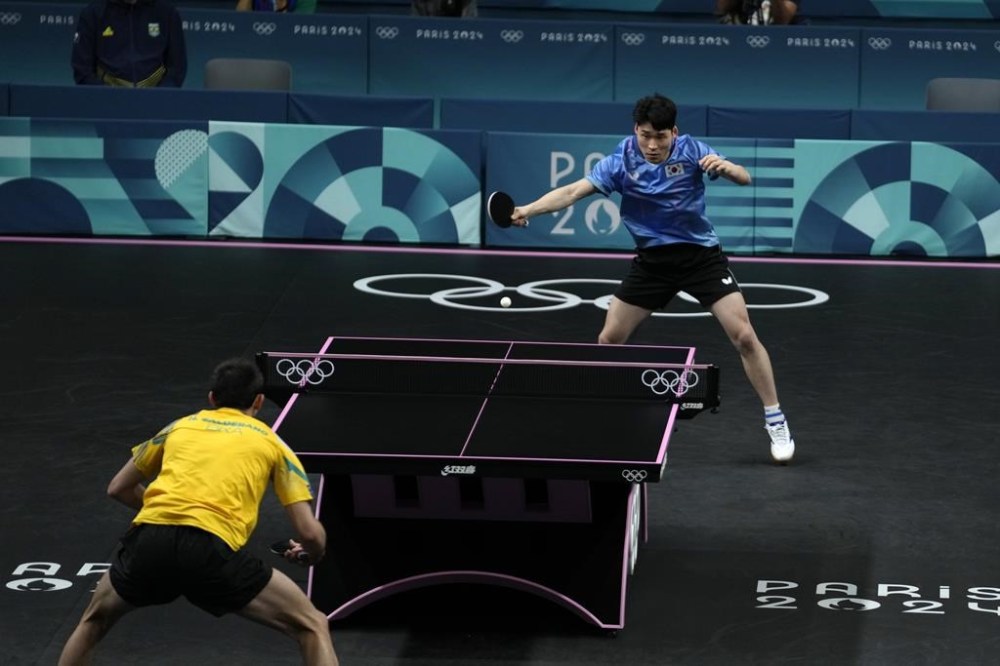 Brazil's Hugo Calderano, foreground, plays against South Korea's Jang Woojin during a men's singles quarterfinal table tennis match at the 2024 Summer Olympics, Thursday, Aug. 1, 2024, in Paris, France. (AP Photo/Petros Giannakouris)