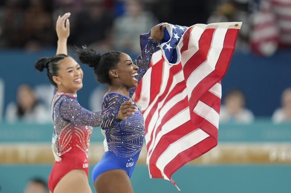 Simone Biles, right, celebrates after winning the gold medal with alongside teammate and bronze medalist Suni Lee, of the United States, during the women's artistic gymnastics all-around finals in Bercy Arena at the 2024 Summer Olympics, Thursday, Aug. 1, 2024, in Paris, France. (AP Photo/Abbie Parr)