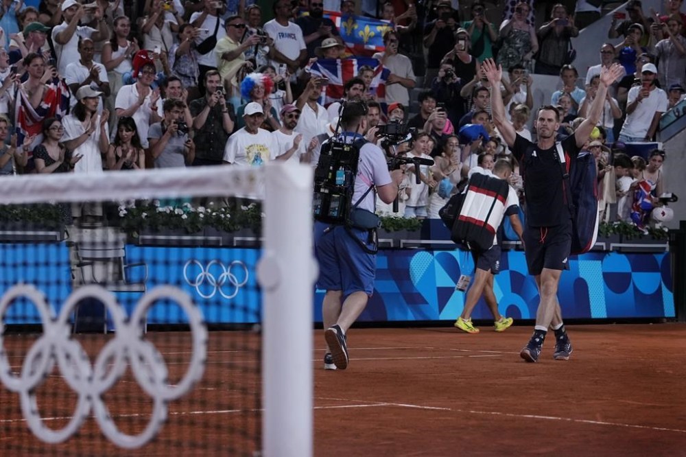 Andy Murray of Britain waves to the spectators as he and his partner Daniel Evans leave the court after defeated by Taylor Fritz and Tommy Paul of the United States in the men's doubles quarterfinals tennis match, at the 2024 Summer Olympics, Thursday, Aug.1, 2024, at the Roland Garros stadium in Paris, France. (AP Photo/Andy Wong)
