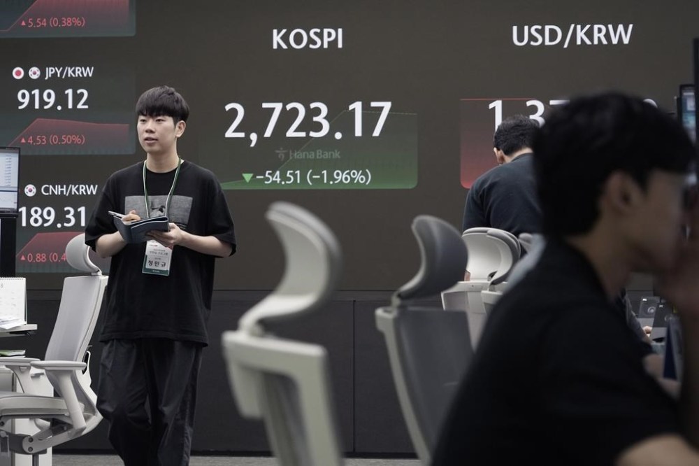 A currency trader passes by the screen showing the Korea Composite Stock Price Index (KOSPI) at the foreign exchange dealing room of the KEB Hana Bank headquarters in Seoul, South Korea, Friday, Aug. 2, 2024. (AP Photo/Ahn Young-joon)