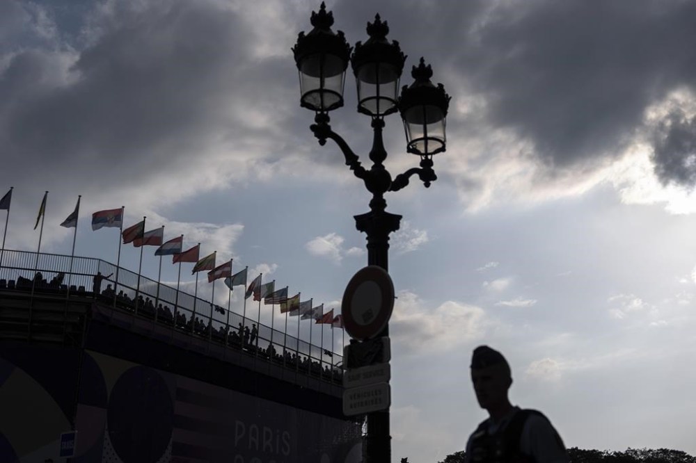 A police officer patrols outside the venue as spectators watch a 3x3 basketball game from the stands at the 2024 Summer Olympics, Thursday, Aug. 1, 2024, in Paris, France. (AP Photo/David Goldman)