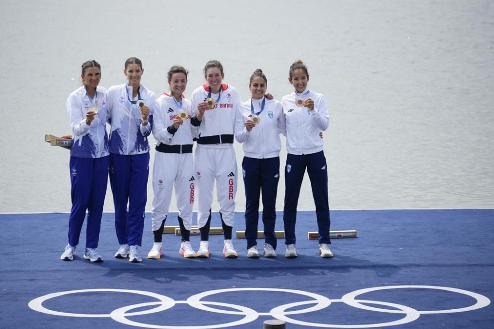 Silver medalists, left, Romania's Ionela Livia Cozmiuc and Gianina Elena van Groningen, gold medalists, center Britain's Emily Craig and Imogen Grant and bronze medalists Greece's Dimitra Kontou and Zoi Fitsiou pose for photos during a medals ceremony in the women's lightweight double sculls rowing final at the 2024 Summer Olympics, Friday, Aug. 2, 2024, in Vaires-sur-Marne, France. (AP Photo/Ebrahim Noroozi)
