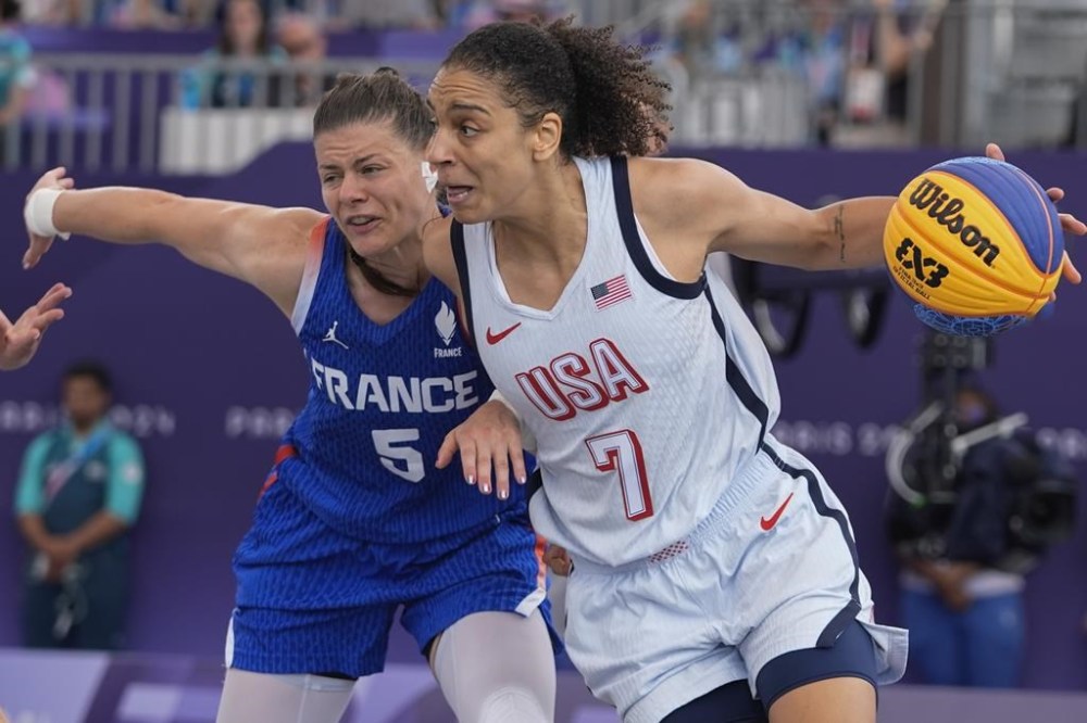 Cierra Burdick (7), of the United States, drives past Marie Eve Paget (5), of France, in the women's 3x3 basketball pool round match during the 2024 Summer Olympics, Friday, Aug. 2, 2024, in Paris, France. The United States won 14-13. (AP Photo/Frank Franklin II)