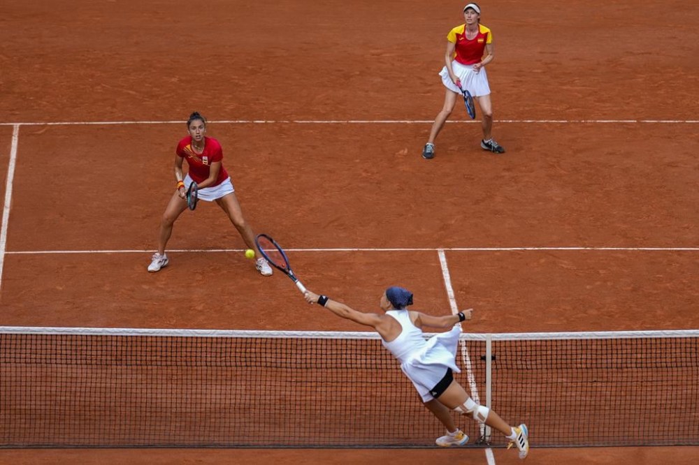 Diana Shnaider, down, returns the ball next to her teammate Mirra Andreeva of Individual Neutral Athlete compete against Cristina Bucsa and Sara Sorribes Tormo of Spain during women's doubles semifinals tennis match at the Roland Garros stadium, at the 2024 Summer Olympics, Friday, Aug. 2, 2024, in Paris, France. (AP Photo/Manu Fernandez)