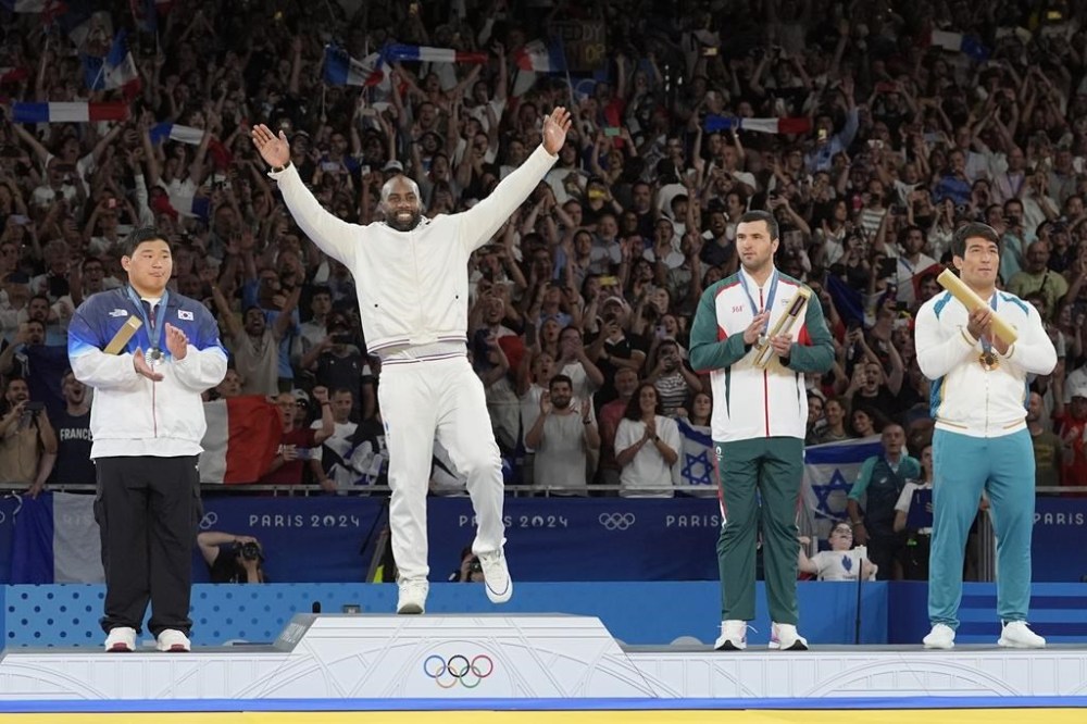 Medal winners, from left, South Korea's Min-Jong Kim, silver, France's Teddy Riner, gold, Tajikistan's Temur Rakhimov, Uzbekistan's Alisher Yusupov, bronze, celebrate on the podium of the judo men's +100 kg event in the team judo competition, at Champ-de-Mars Arena, during the 2024 Summer Olympics, Friday, Aug. 2, 2024, in Paris, France. (AP Photo/Eugene Hoshiko)