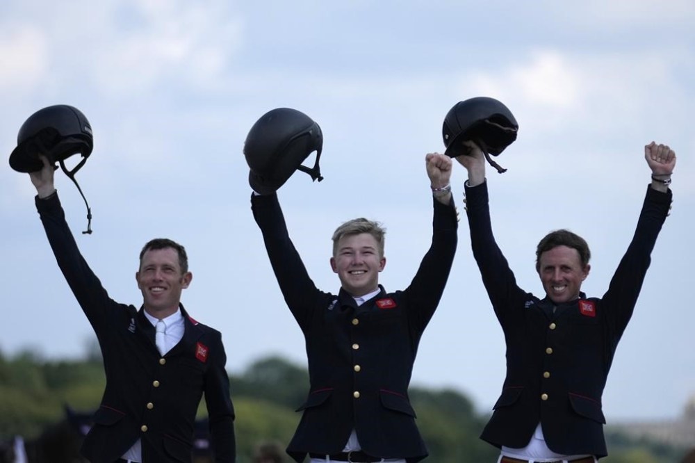 Britain's Scott Brash, right, Harry Charles, center, and Ben Maher celebrate after winning the gold medal the Equestrian Jumping Team final at the 2024 Summer Olympics, Friday, Aug. 2, 2024, in Versailles, France. (AP Photo/=03387382=)