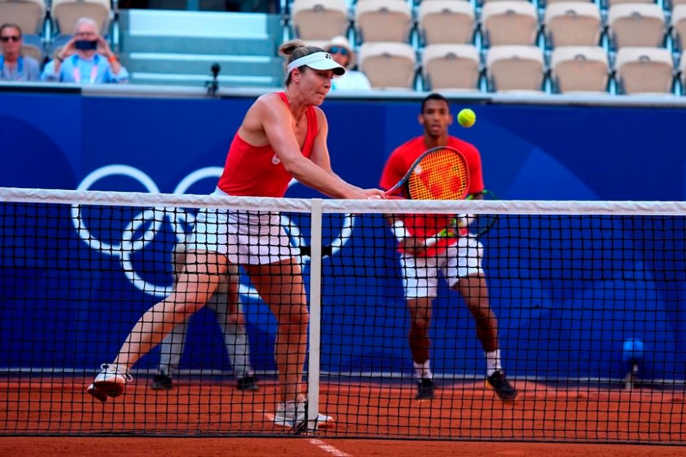 Canada's Gabriela Dabrowski plays a volley while Felix Auger-Aliassime looks on during the mixed doubles bronze-medal match against Demi Schuurs and Wesley Koolhoof of the Netherlands at the Summer Olympics in Paris on Friday, Aug.2, 2024. THE CANADIAN PRESS/Adrian Wyld