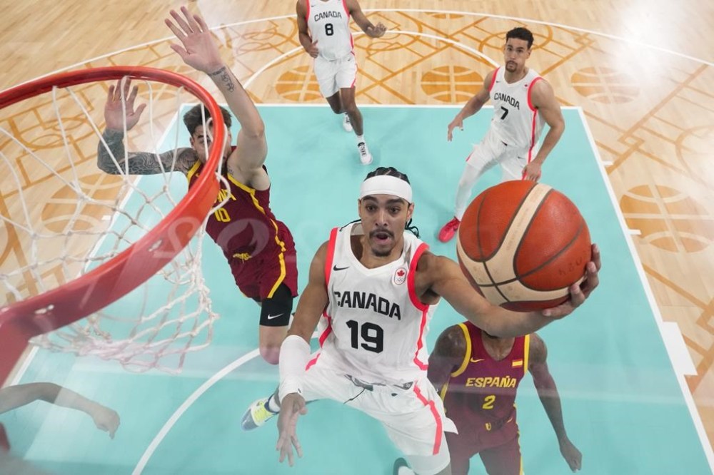Andrew Nembhard, of Canada, shoots in front of Juancho Hernangomez, left, and Lorenzo Brown, of Spain, in a men's basketball game at the 2024 Summer Olympics, Friday, Aug. 2, 2024, in Villeneuve-d'Ascq, France. (AP Photo/Mark J. Terrill, Pool)
