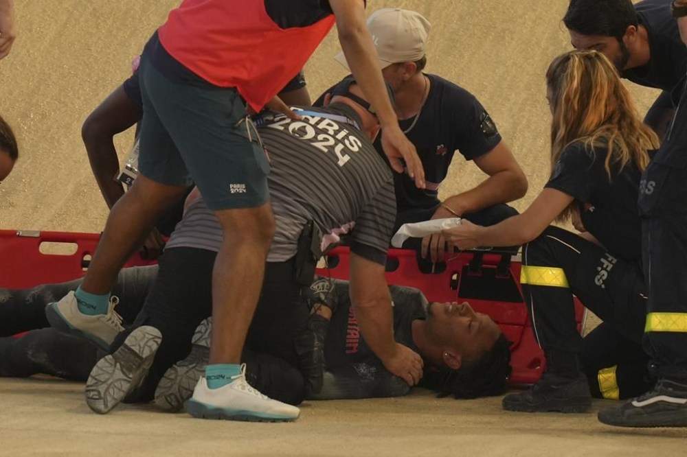 Kye Whyte of Britain receives medical assistance after crashing during a BMX racing event, at the 2024 Summer Olympics, Friday, Aug. 2, 2024, in Saint-Quentin-en-Yvelines, France. (AP Photo/Thibault Camus)