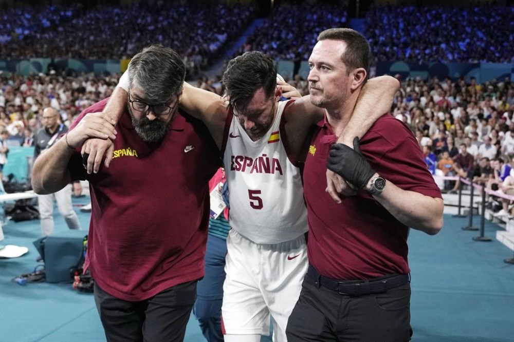 Spain's Rudy Fernandez, center, is held off the court after being injured in a men's basketball game against Greece at the 2024 Summer Olympics, Tuesday, July 30, 2024, in Villeneuve-d'Ascq, France. (AP Photo/Michael Conroy)