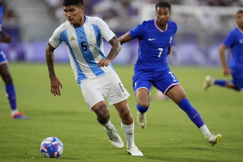 Argentina's Bruno Amione fights for the ball with France's Michael Olise during a quarter final soccer match between France and Argentina, at Bordeaux Stadium, during the 2024 Summer Olympics, Friday, Aug. 2, 2024, in Bordeaux, France. (AP Photo/Rebecca Blackwell)
