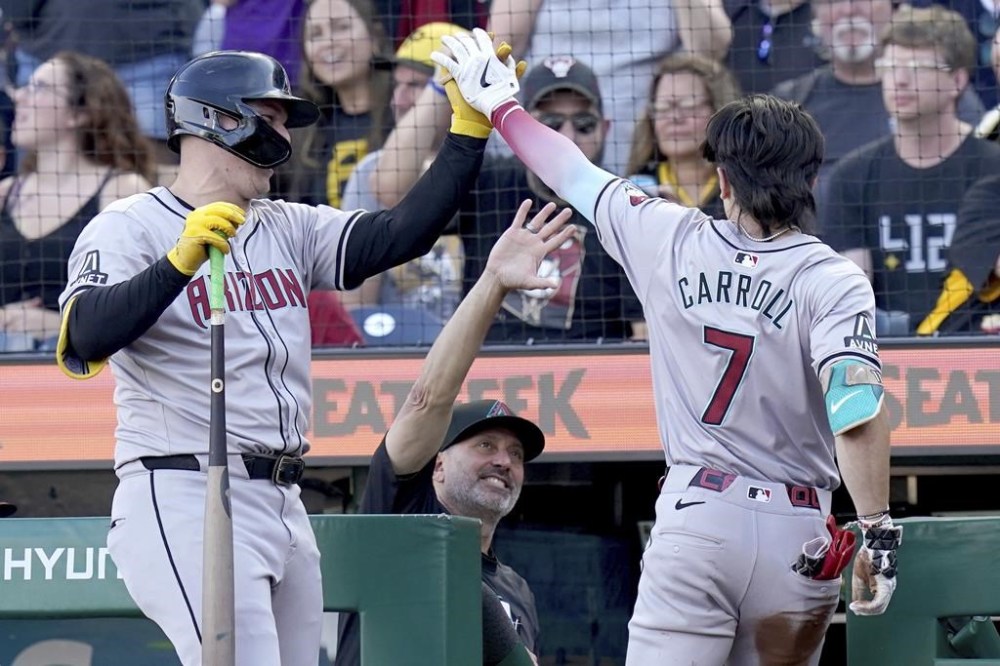 Arizona Diamondbacks' Corbin Carroll, right, is greeted by Joc Pederson, left, and manager Torey Lovullo, center, after scoring during the first inning of a baseball game against the Pittsburgh Pirates, Friday, Aug. 2, 2024, in Pittsburgh. (AP Photo/Matt Freed)