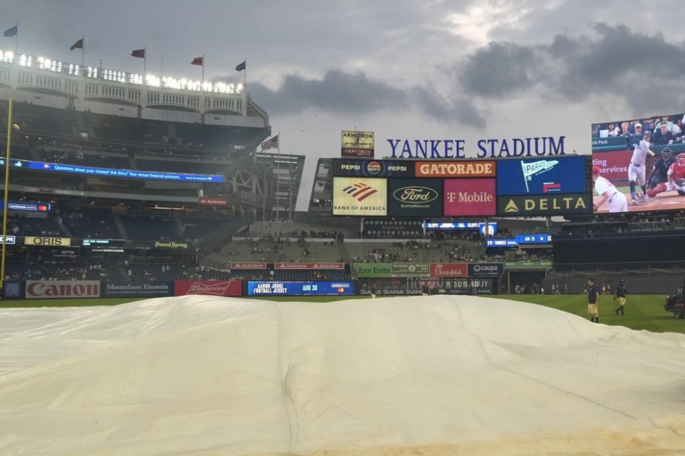 Yankee Stadium staff set up a tarp on the field as it rains before a baseball game between the New York Yankees and the Toronto Blue Jays, Friday, Aug. 2, 2024, in New York. (AP Photo/Pamela Smith)