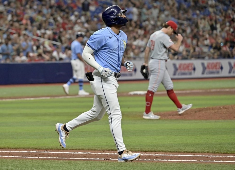 Tampa Bay Rays' Richie Palacios jogs to first base after walking in the go-ahead run from Cincinnati Reds reliever Lucas Sims, right, during the eighth inning of a baseball game, Sunday, July 28, 2024, in St. Petersburg, Fla. (AP Photo/Steve Nesius)