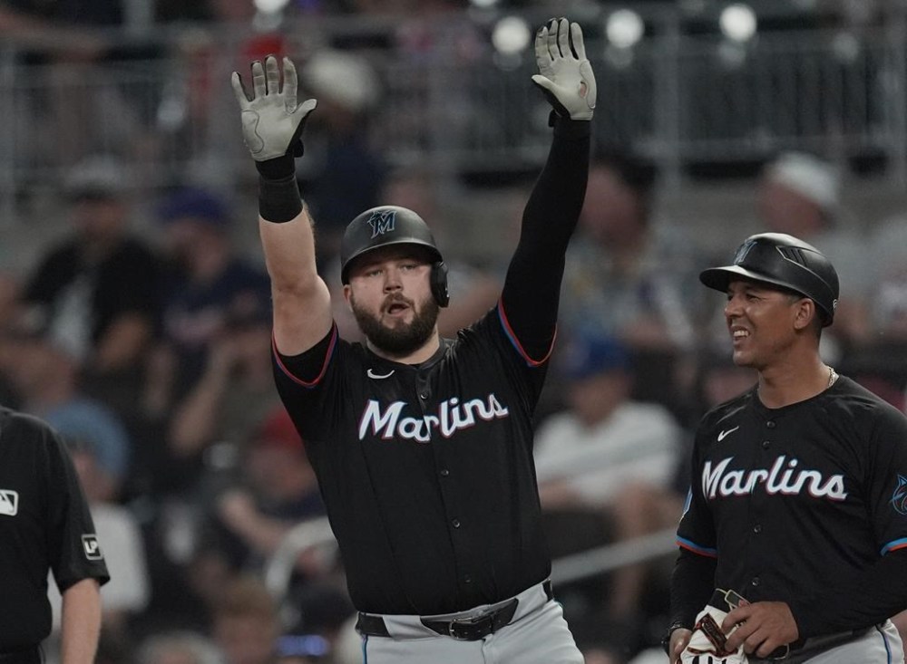 Miami Marlins' Jake Burger gestures to his teammates in the dugout after driving in a run with a base hit in the seventh inning of a baseball game against the Atlanta Braves, Thursday, Aug. 1, 2024, in Atlanta. (AP Photo/John Bazemore)