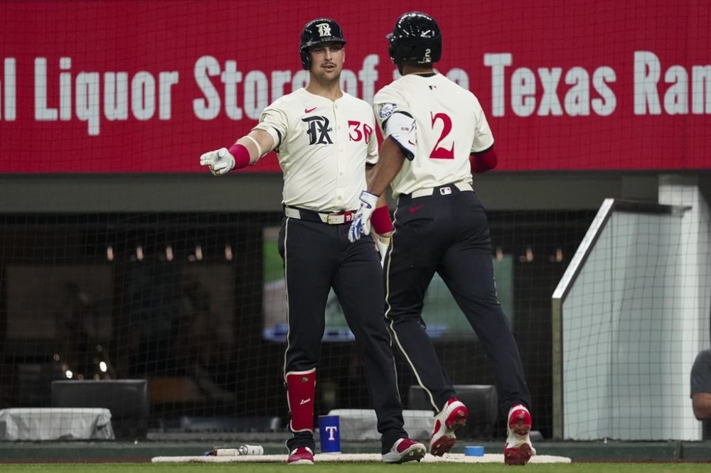 Texas Rangers' Marcus Semien (2) is congratulated by Nathaniel Lowe (30) after hitting a two-run home run during the sixth inning of a baseball game against the Boston Red Sox, Friday, Aug. 2, 2024, in Arlington, Texas. (AP Photo/Sam Hodde)
