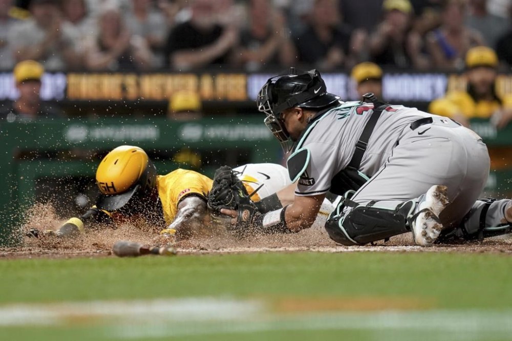 Pittsburgh Pirates' Andrew McCutchen, left, slides safely into home ahead of a tag by Arizona Diamondbacks catcher Gabriel Moreno, right, during the sixth inning of a baseball game Friday, Aug. 2, 2024, in Pittsburgh. (AP Photo/Matt Freed)