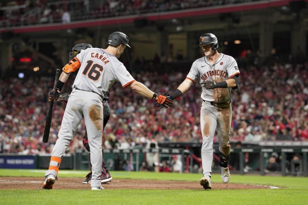 San Francisco Giants' Tyler Fitzgerald, right, celebrates with teammate Mark Canha (16) after hitting a solo home run during the seventh inning of a baseball game against the Cincinnati Reds, Friday, Aug. 2, 2024, in Cincinnati. (AP Photo/Jeff Dean)