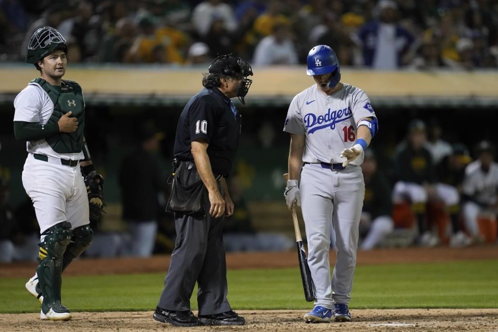 Los Angeles Dodgers' Will Smith, right, talks to home plate umpire Phil Cuzzi, center, after being called out on strikes during the eighth inning of a baseball game against the Oakland Athletics, Friday, Aug. 2, 2024, in Oakland, Calif. (AP Photo/Godofredo A. Vásquez)