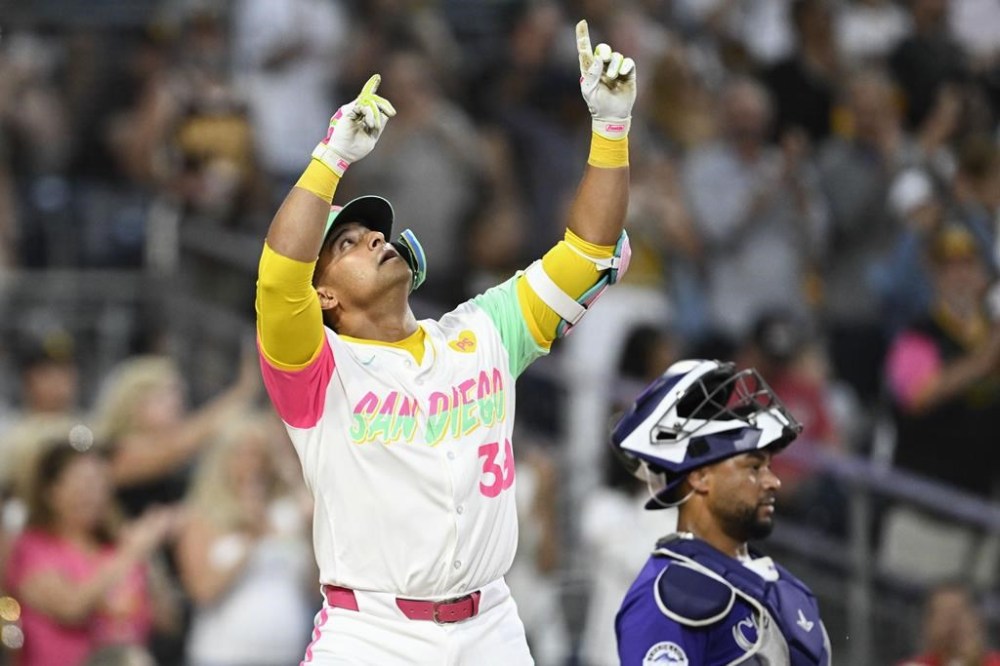 San Diego Padres' Donovan Solano, left, points skyward after hitting a solo home run as Colorado Rockies catcher Elias Diaz, right, looks on during the fourth inning of a baseball game against Friday, Aug. 2, 2024, in San Diego. (AP Photo/Denis Poroy)