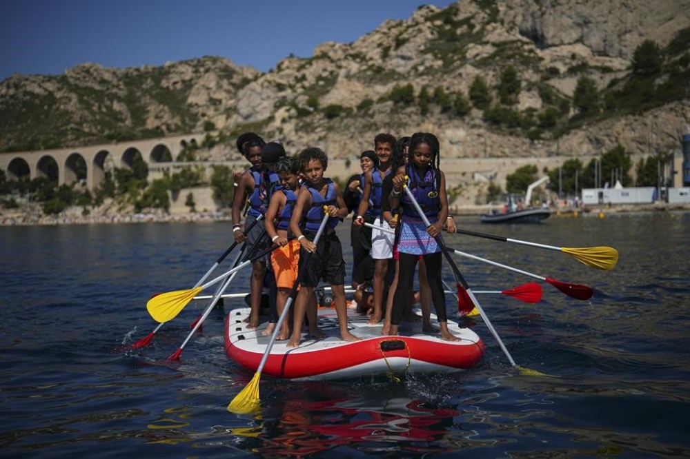 Children attend a swimming camp organized by the Grand Bleu Association which facilitates access to the sea for marginalized children in Marseille, France, Friday, July 26, 2024. Marseille, a millenniums-old port, is a crossroads of cultures and faiths, where the sea is ever present but not equally accessible, and the beauty and cosmopolitan flair rub shoulders with enclaves of poverty and exclusion even more intimately than in the rest of France. (AP Photo/Daniel Cole)