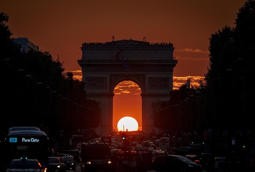 The setting sun, framed by the Arc de Triomphe, illuminates the Champs-Élysées during the 2024 Summer Olympics, Friday, Aug. 2, 2024, in Paris, France. (AP Photo/Vadim Ghirda)