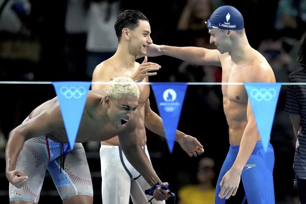 Leon Marchand, right, from France and his teammates celebrate winning a men's 4x100-meter medley relay heat at the Summer Olympics in Nanterre, France, Saturday, Aug. 3, 2024. (AP Photo/Natacha Pisarenko)