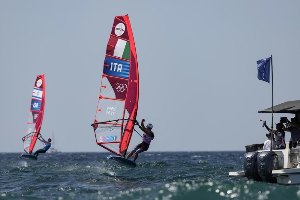Marta Maggetti of Italy celebrates as she crosses the finish line of the final race ahead of Sharon Kantor of Israel to win the women's iQFOiL windsurfing class gold medal during the 2024 Summer Olympics, Saturday, Aug. 3, 2024, in Marseille, France. (AP Photo/Carolyn Kaster)