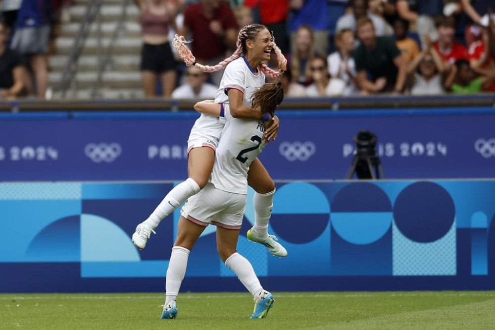 Trinity Rodman of the United States, top, celebrates after scoring the opening goal during the quarterfinal women's soccer match between the United States and the Japan at the Parc des Princes at the 2024 Summer Olympics, Saturday, Aug. 3, 2024, in Paris, France. (AP Photo/Aurelien Morissard)