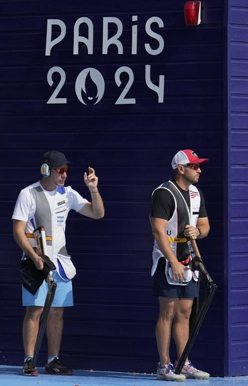 Vincent Hancock of the United States, right, and Argentina's Federico Gil wait for their turn to shoot in the Skeet men's qualification round at the 2024 Summer Olympics, Saturday, Aug. 3, 2024, in Chateauroux, France. (AP Photo/Manish Swarup)