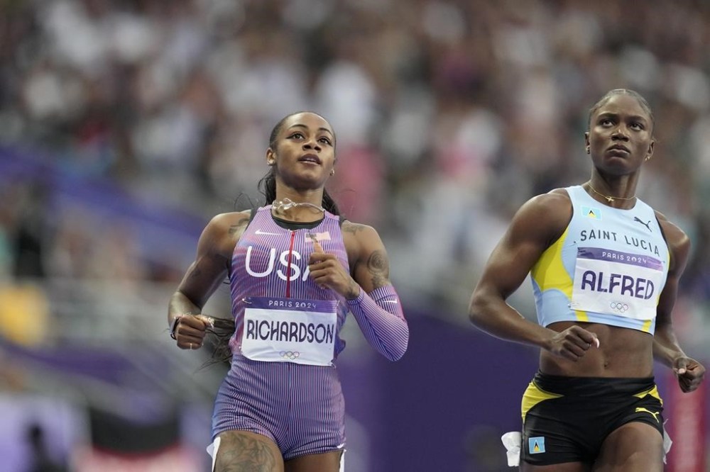 Sha'carri Richardson, of the United States, and Julien Alfred, of Saint Lucia, check the results after finishing a women's 100 meters semifinal at the 2024 Summer Olympics, Saturday, Aug. 3, 2024, in Saint-Denis, France. (AP Photo/Ashley Landis)
