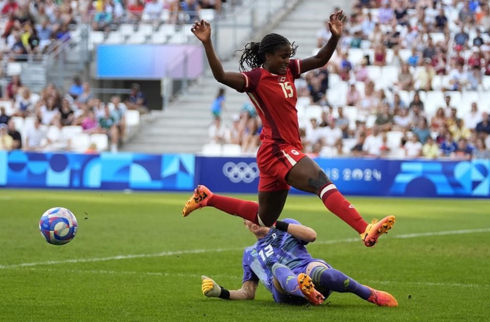 Canada's Nichelle Prince jumps over Germany goalkeeper Ann-Katrin Berger during a women's quarterfinal soccer match between Canada and Germany at the 2024 Summer Olympics, Saturday, Aug. 3, 2024, at Marseille Stadium in Marseille, France. THE CANADIAN PRESS/AP-Julio Cortez